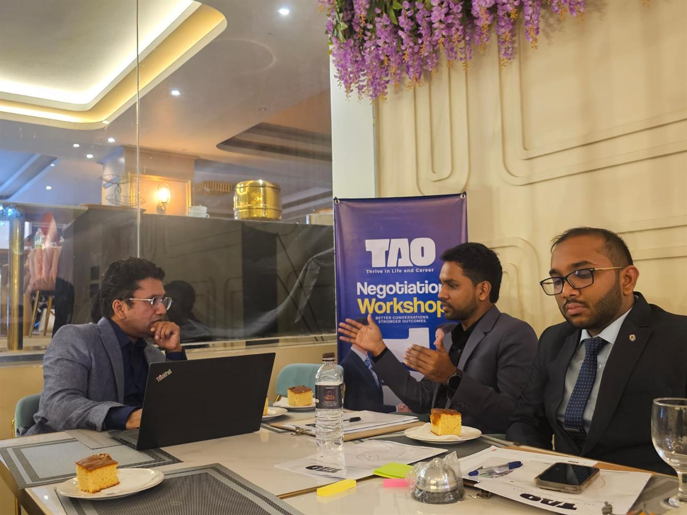 Three people in discussion during a negotiation simulation at a TAO workshop
